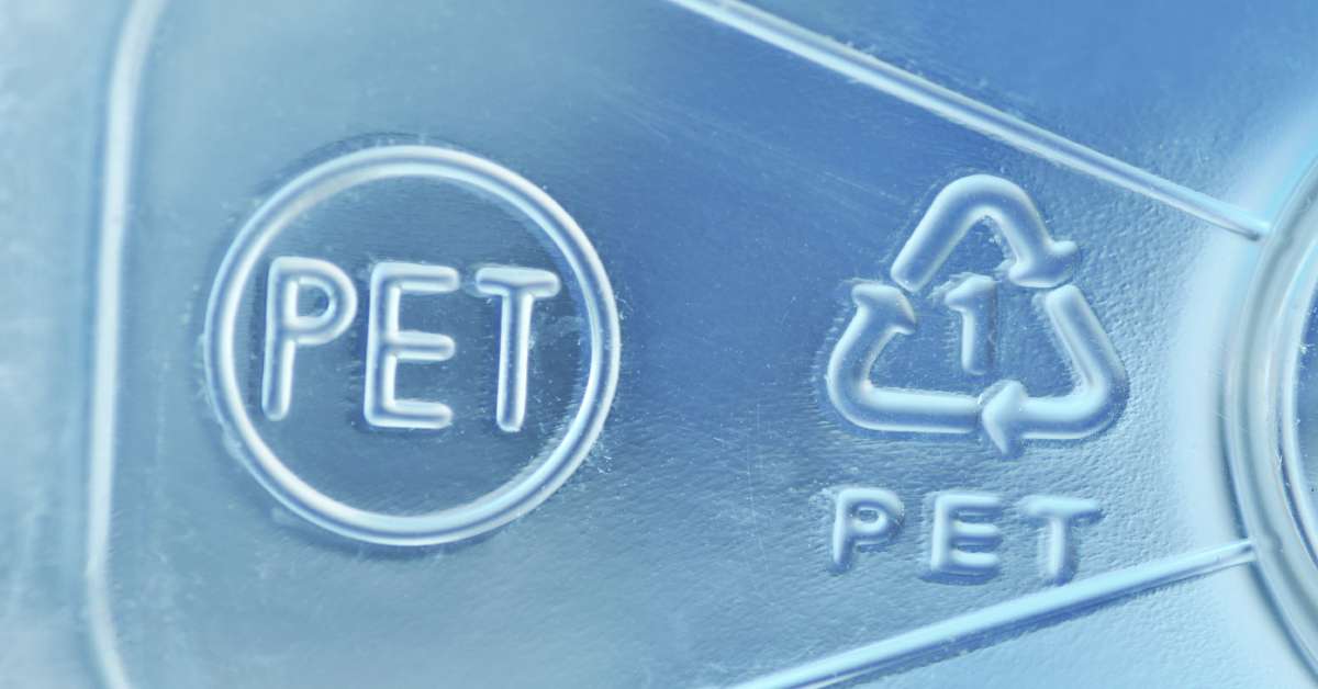 A close-up of a plastic product's recycling symbols: a circle with the letters "PET" and a recycling sign with the number "1"